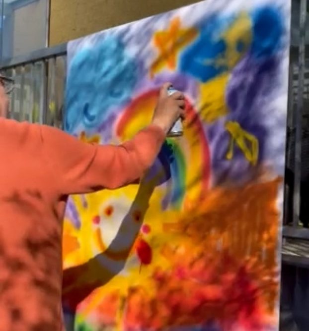 Teilnehmer sprayt Bild zur Verschönerung der Tagesstätte