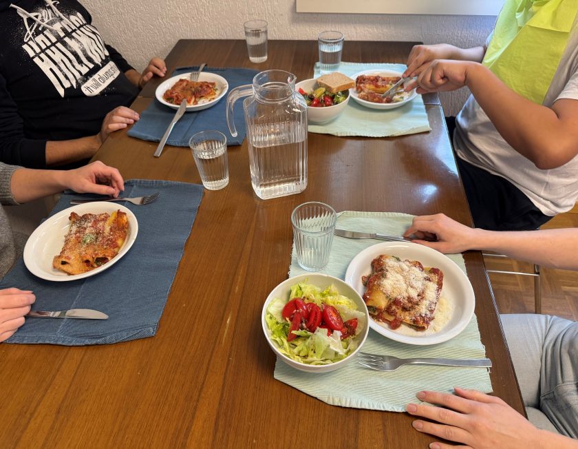 Vier Personen sitzen am Tisch mit frischbereiteten Essen