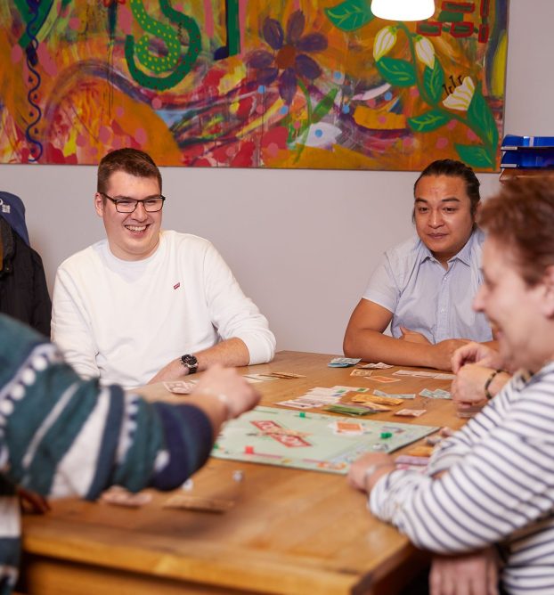 Einige menschen sitzen am Tisch und spielen Monopoly